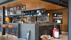 A modern bar area with a counter, bar stools, and shelves with various items. - Moxy Bristol (Bristol)