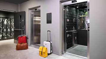 An elevator with a sign listing floor numbers and a luggage stand with suitcases and bags.
