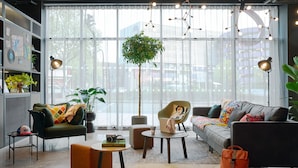 A modern living room with a sofa, armchairs, a coffee table, and a bookshelf. - Moxy Bristol (Bristol)