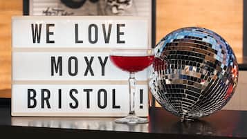 A lightbox with "WE LOVE MOXY BRISTOL!" text, a disco ball, and a red cocktail glass.