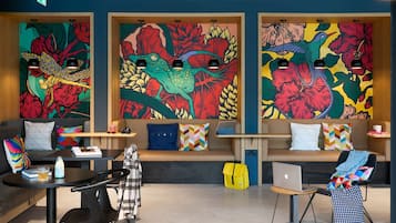 A modern lounge area with colorful murals, a sofa, a table, and a laptop.