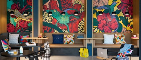 A modern lounge area with colorful murals, a sofa, a table, and a laptop.