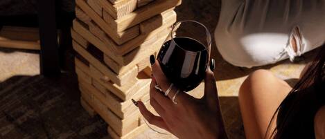 Una persona jugando a un juego de mesa con bloques de madera y sosteniendo una copa de vino tinto.