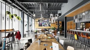 A modern co-working space with long tables, chairs, and a bar area. - Moxy Bristol (Bristol)
