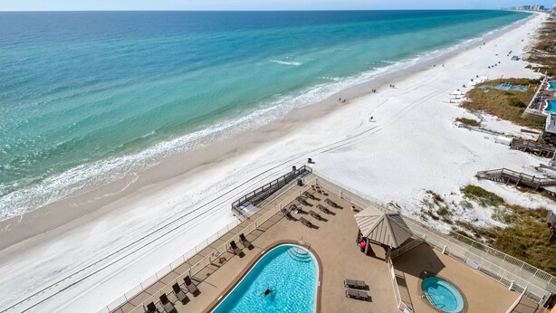 Un resort frente a la playa con zona de piscina, tumbonas y vistas al océano.