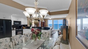 Una cocina amplia con electrodomésticos modernos, un comedor con mesa de vidrio y vista al océano.