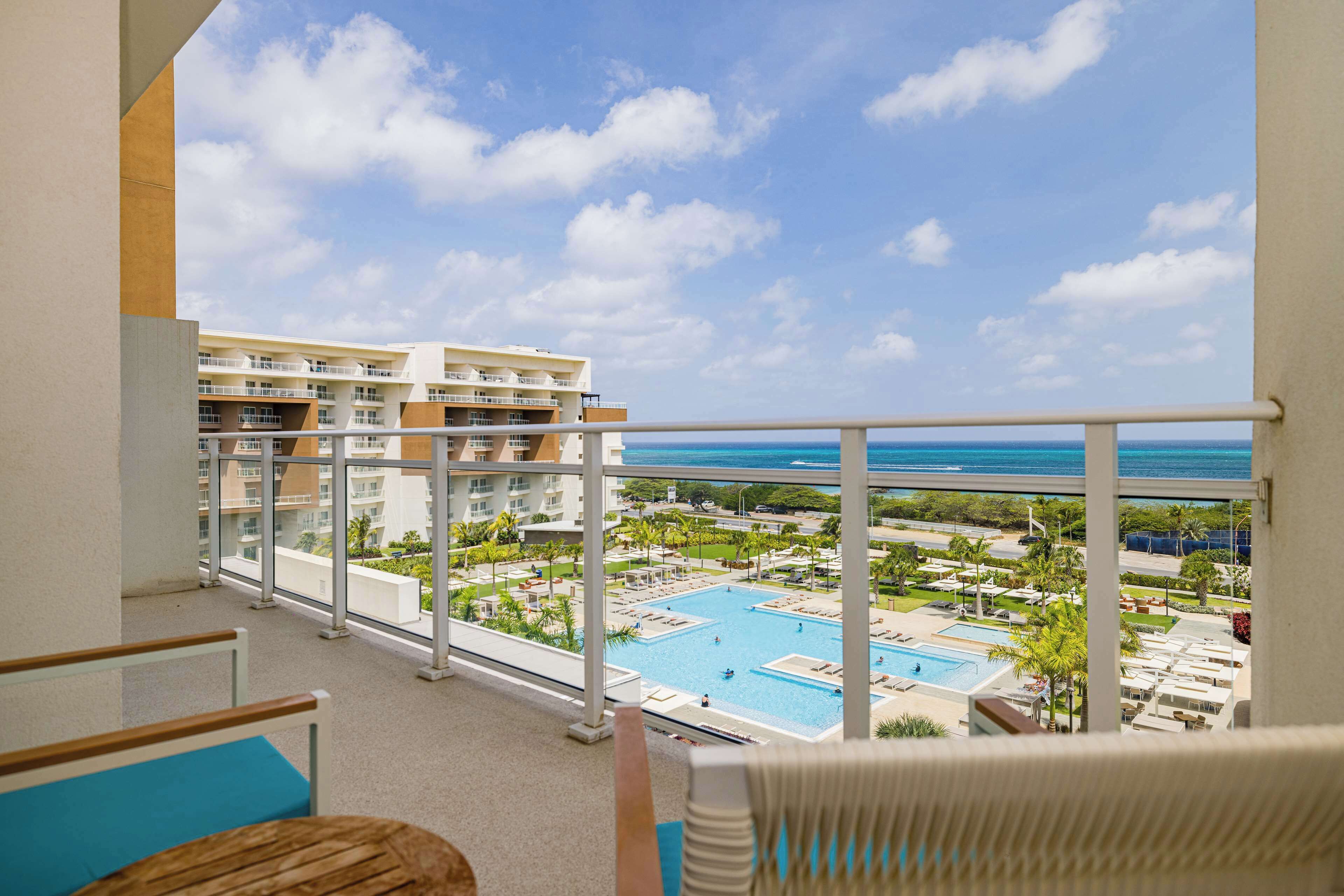 A balcony with a view of a swimming pool and resort buildings.