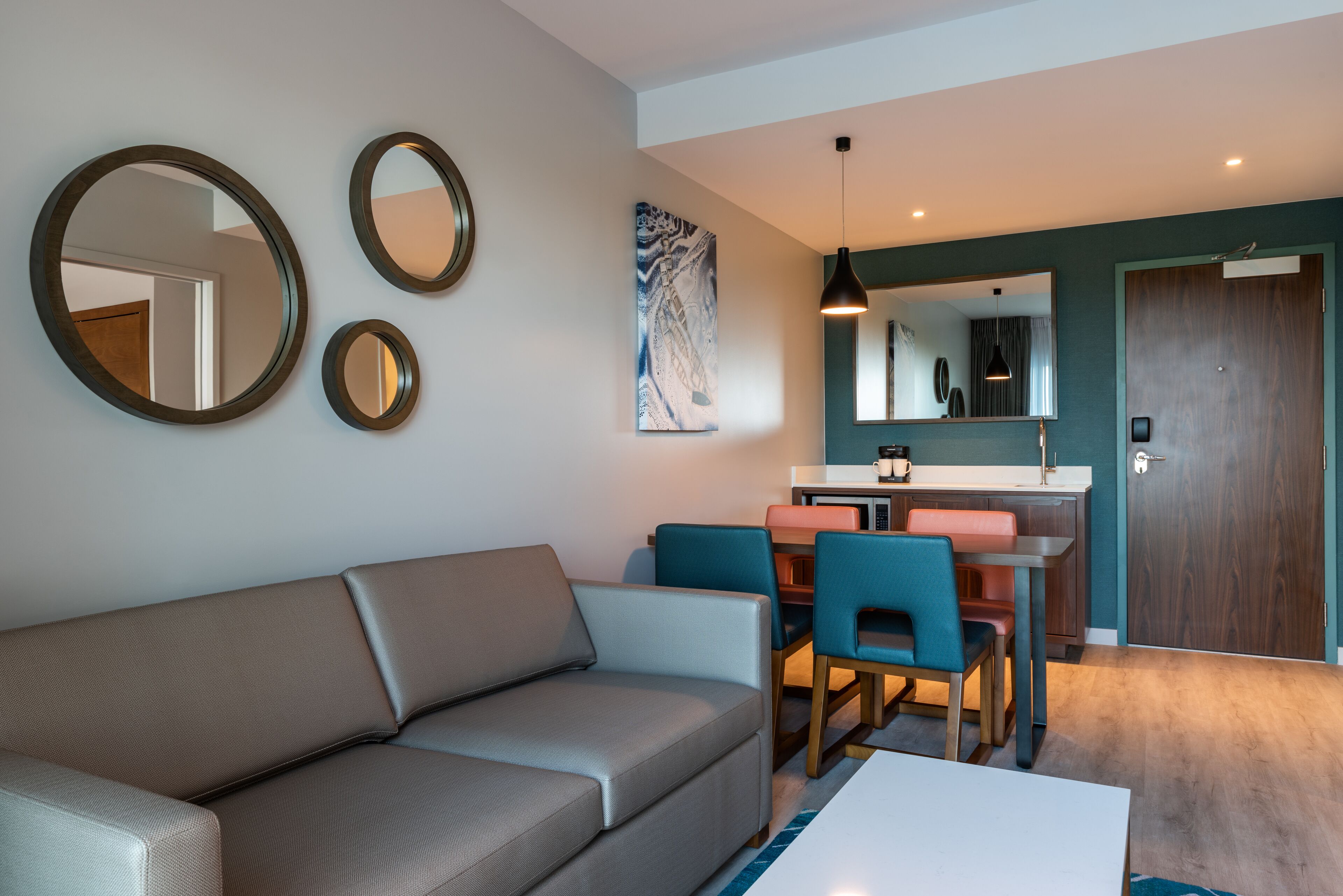 Un salon moderne comprenant un canapé, une table à manger avec des chaises, un coin cuisine et une porte.