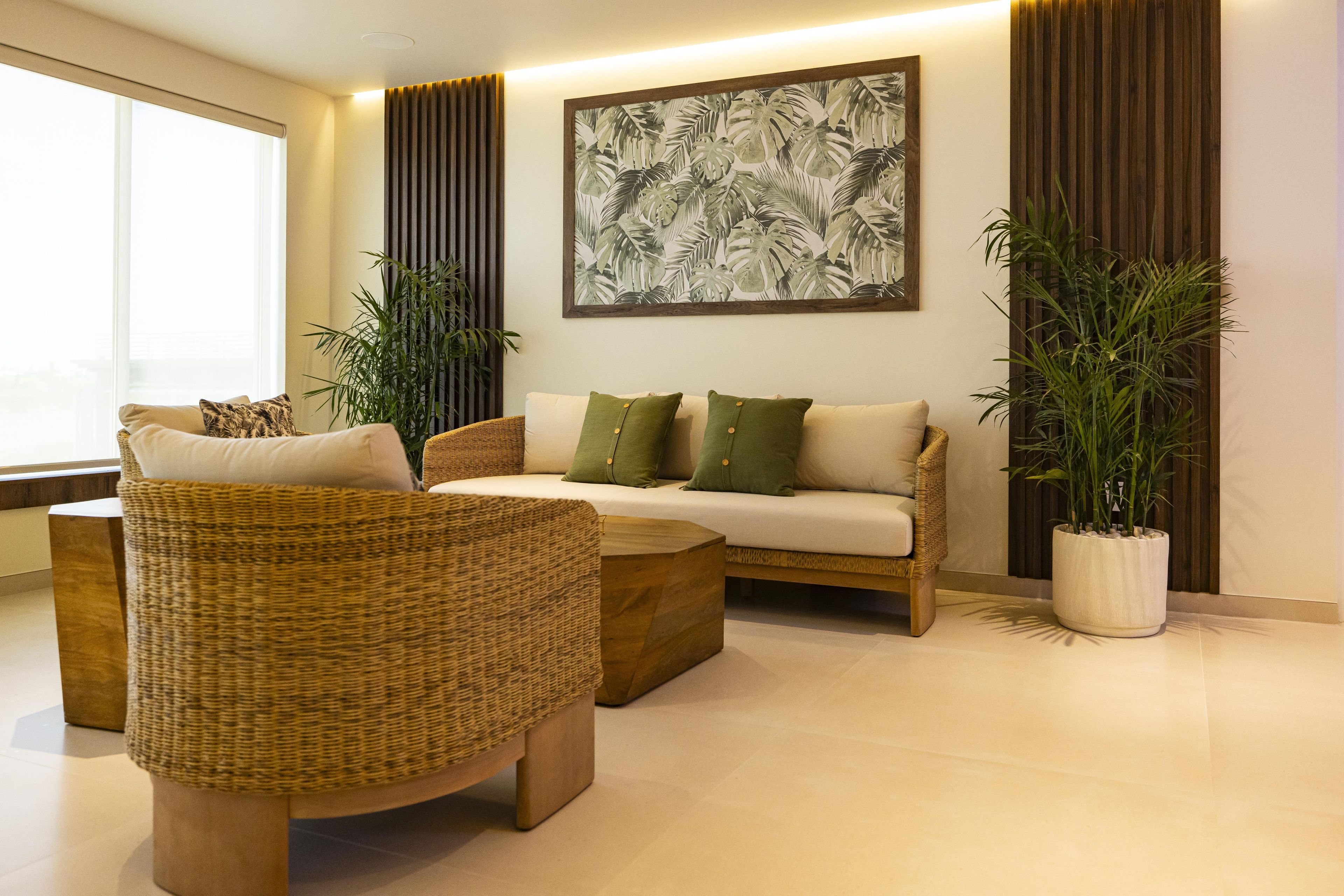 Una sala de estar moderna con un sofá, sillones y una mesa de centro. Hay dos plantas en macetas y una obra de arte grande en la pared.