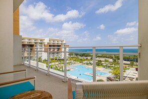 Een balkon met uitzicht op een resort zwembad en de oceaan.