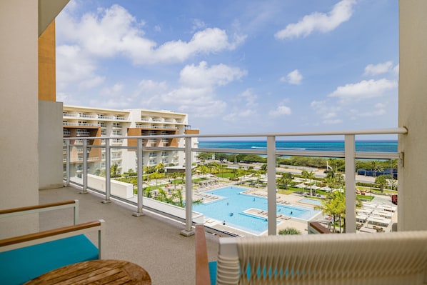 Un balcón con vistas a la piscina y al océano de un resort.