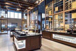 Amplia zona de buffet con diversas opciones de comida y un espacio de estar con mesas y sillas.
