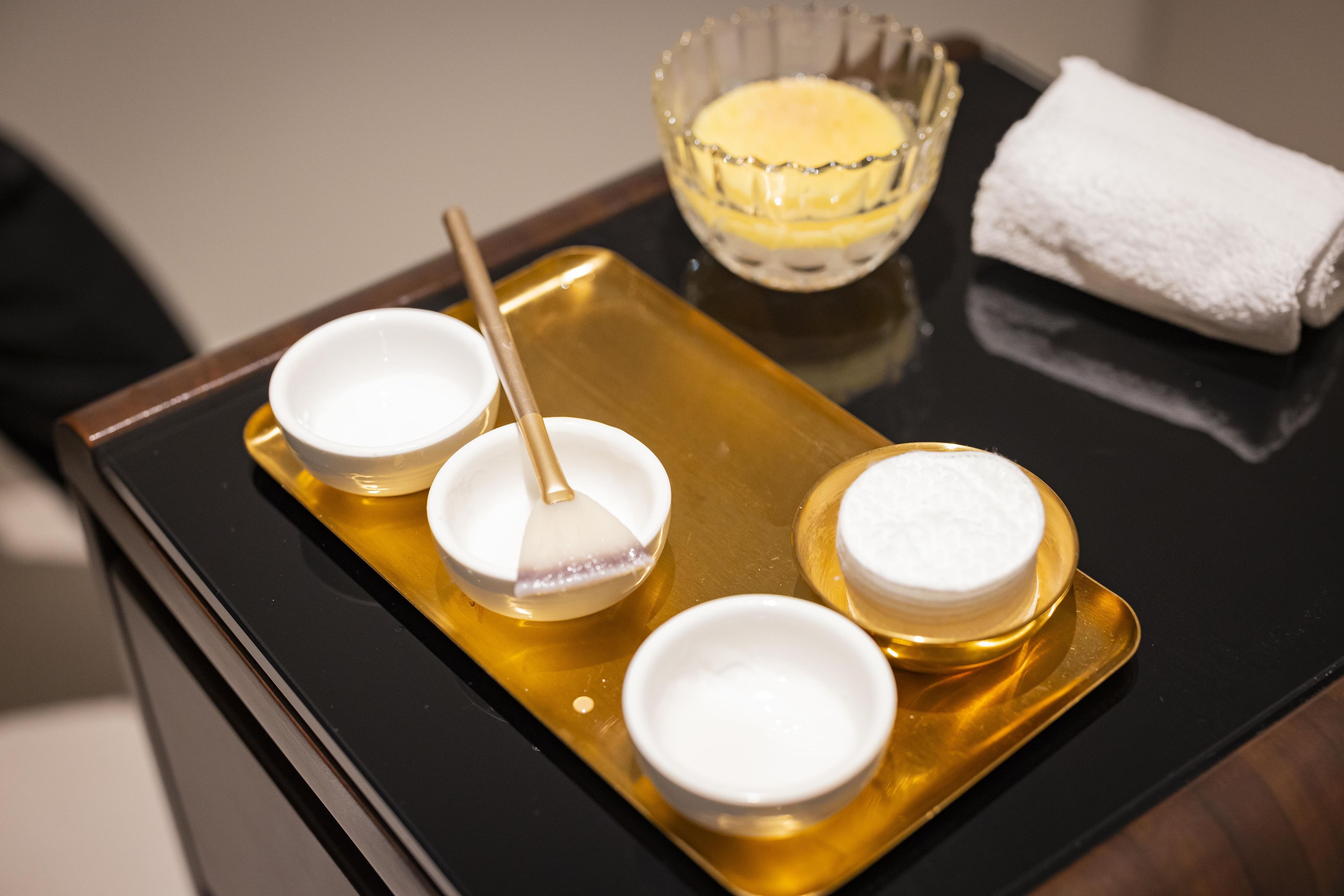 A tray with four bowls of cream and a bowl of butter on a reflective surface.