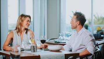 Una mesa de comedor con dos personas sentadas, una copa de vino y un tazón de comida.