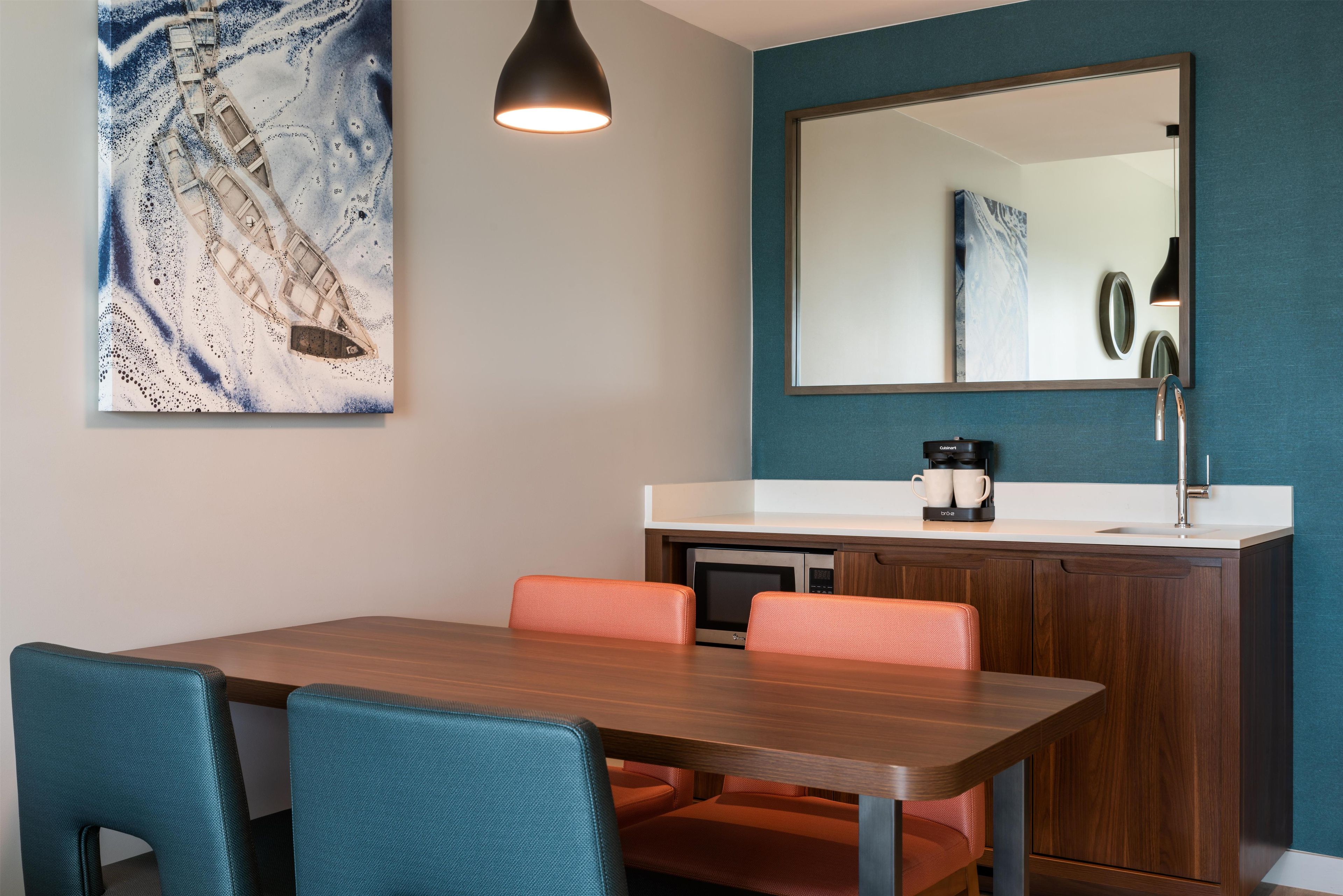 A modern kitchen with a dining table, chairs, a coffee maker, and a microwave.