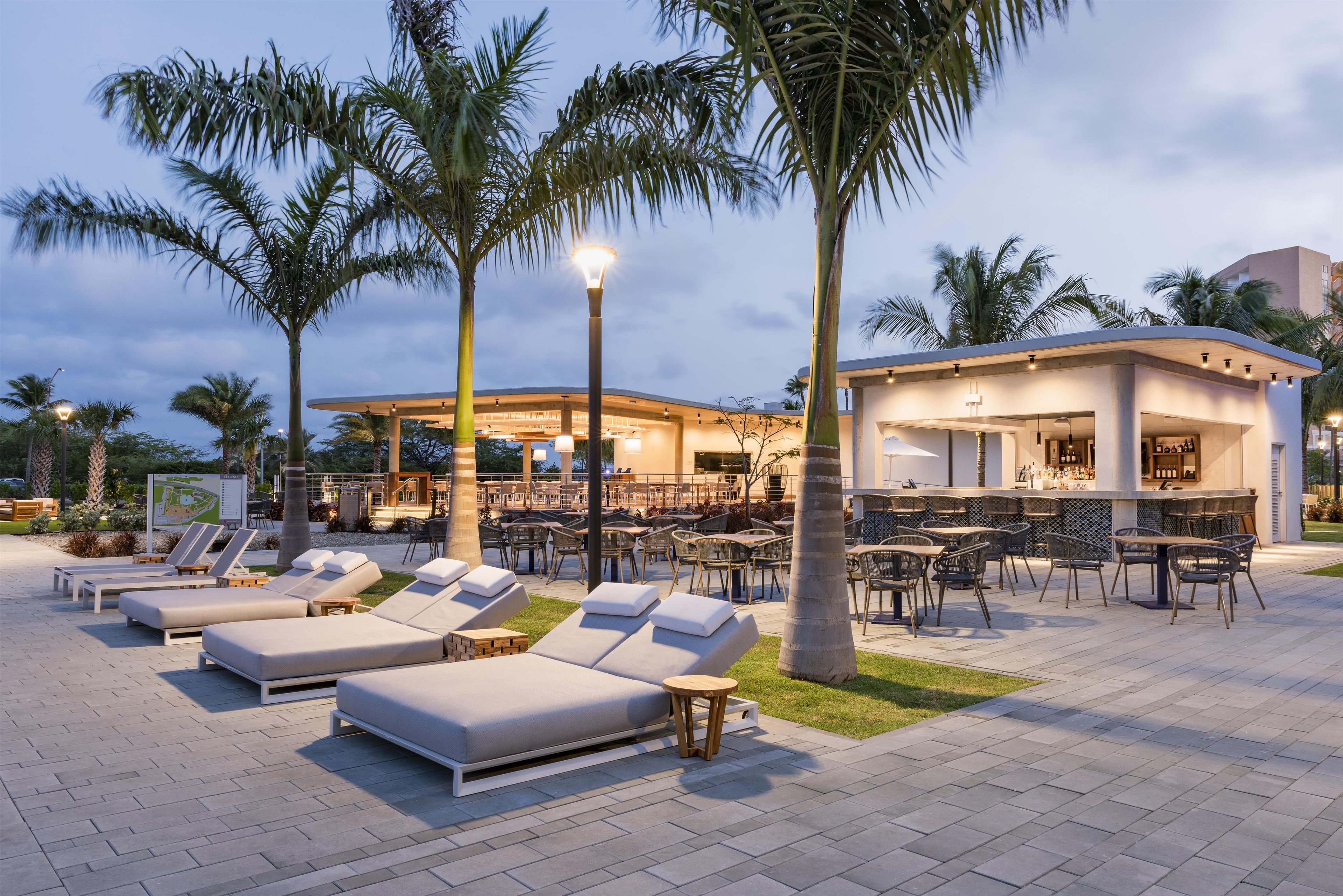 Ein Resort mit Außenbereich, Palmen und einer Bar.