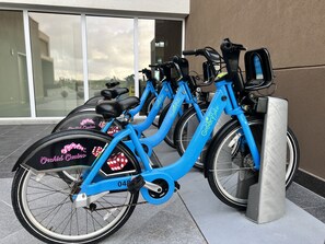 Una fila de bicicletas eléctricas azules estacionadas frente a una fachada de edificio.