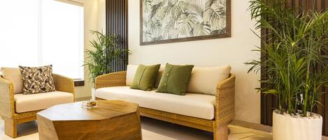 A modern living room with a sofa, two armchairs, a coffee table, and a large potted plant.