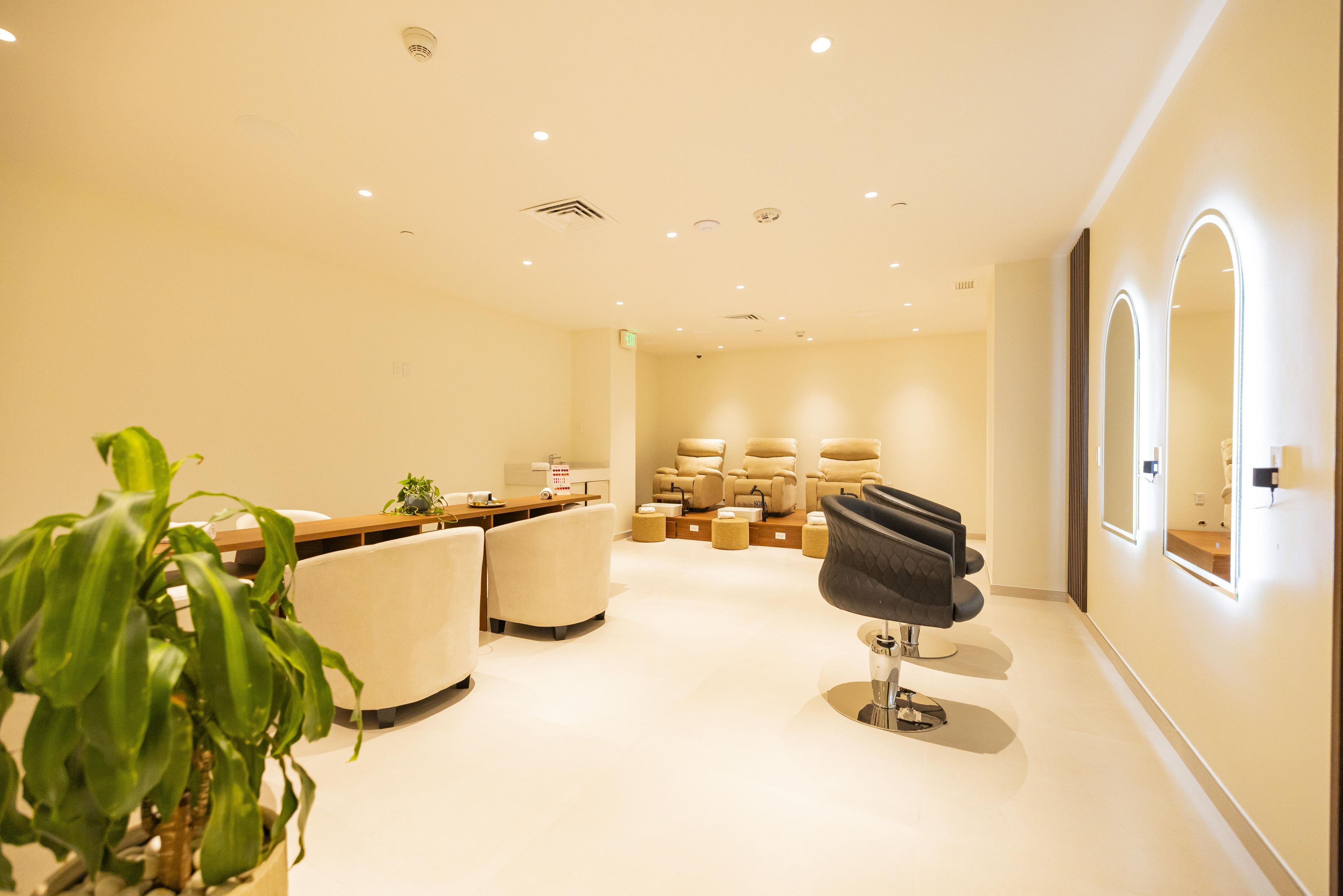 A modern spa with a reception desk, several massage chairs, and a large mirror.