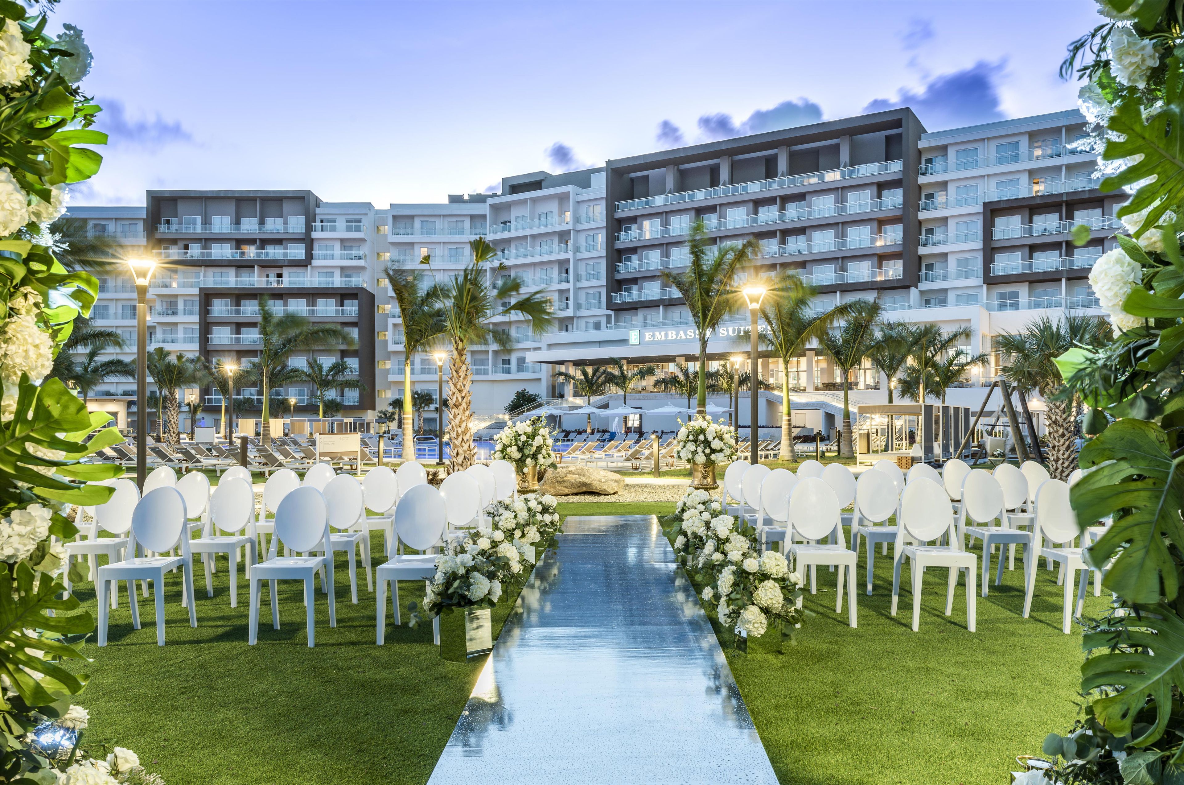 A hotel with multiple floors, outdoor seating, and a well-maintained lawn.