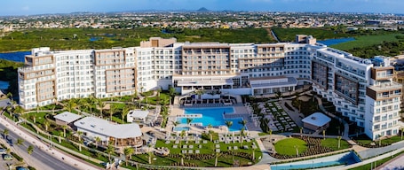 A multi-story hotel with a pool, outdoor seating, and a view of the surrounding landscape.