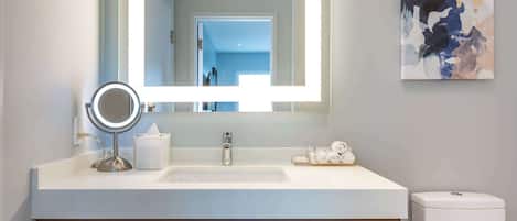 Ein modernes Badezimmer mit großem Spiegel, Waschbecken und Toilette.