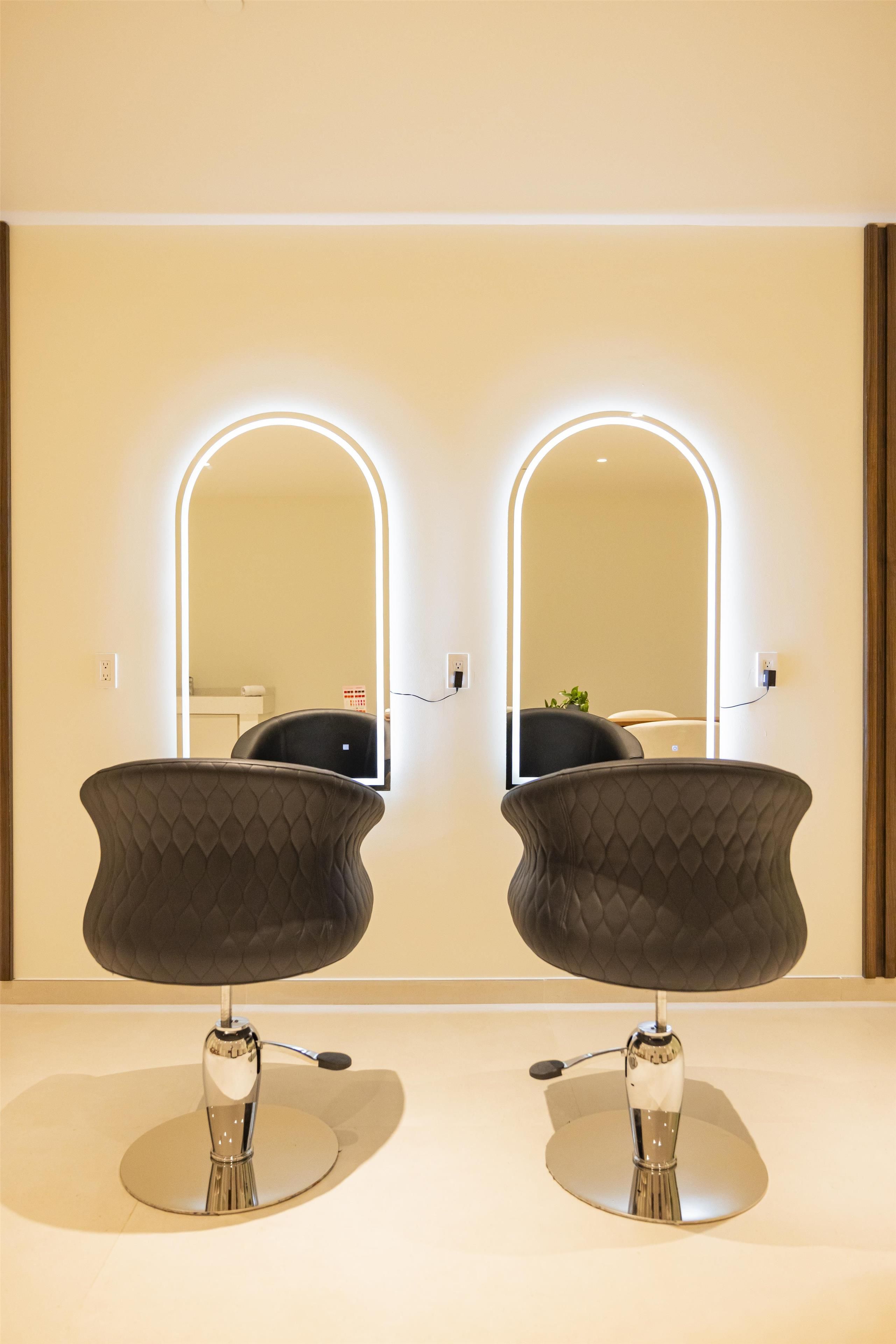 Un baño moderno con dos tocadores con espejo, cada uno con un diseño curvo original y una base cromada.