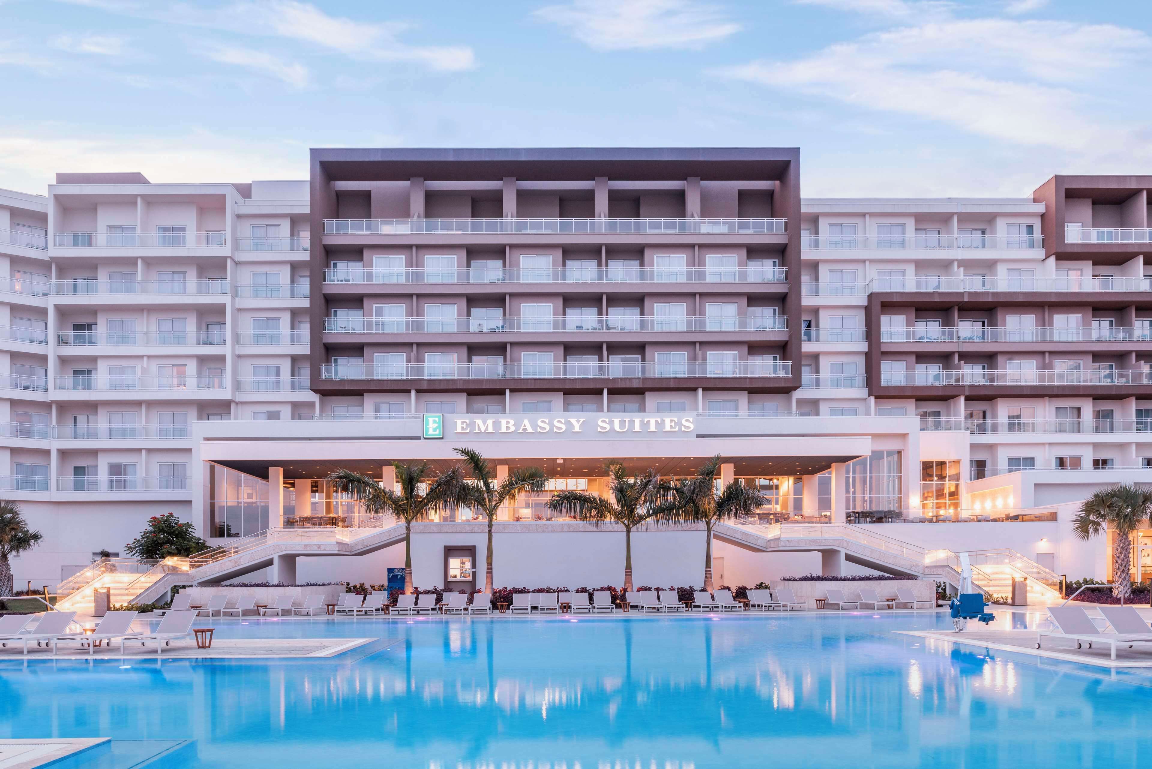Um hotel com várias varandas, área de piscina e uma placa com a inscrição "Embassy Suites".