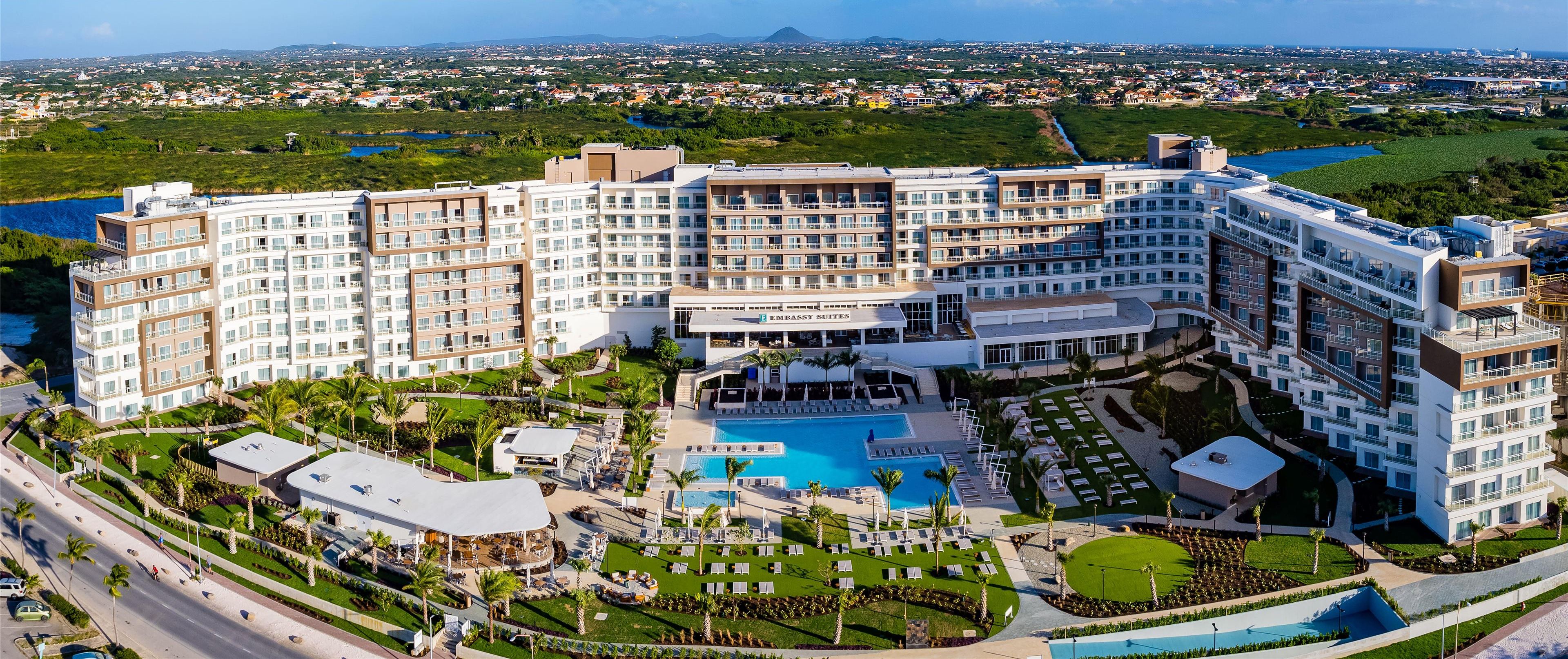 A large hotel with multiple floors, a central pool, and surrounding landscaped areas.