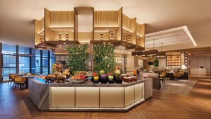 A modern hotel lobby with a central island featuring a buffet, wooden paneling on the ceiling, and large windows providing natural light. - DoubleTree by Hilton Ya'An (Ya'an)