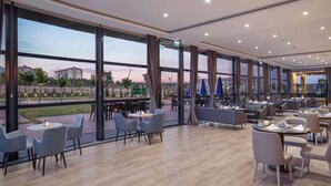 Un amplio comedor interior con ventanas grandes, muebles modernos y vistas al exterior.
