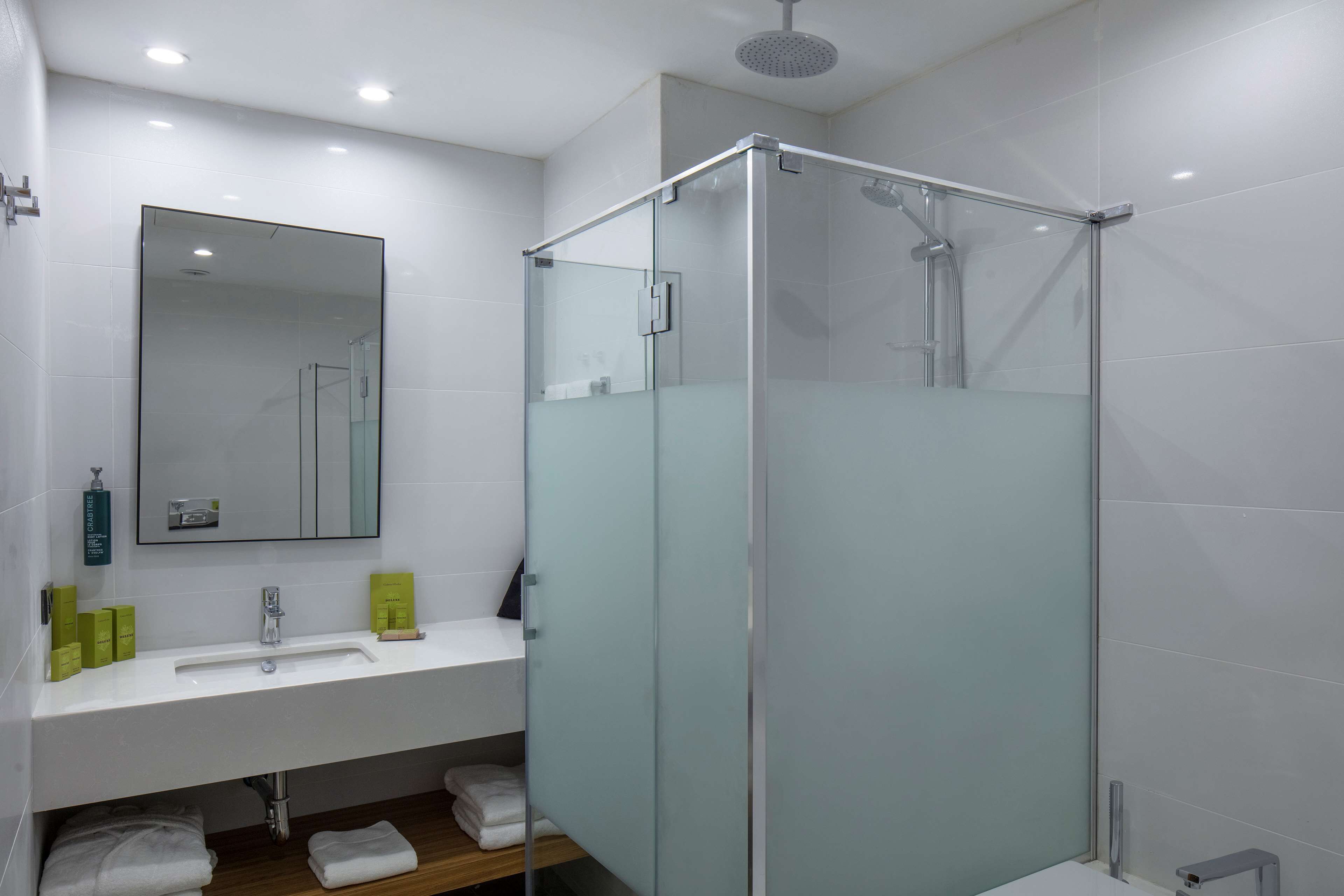 A modern bathroom with a glass-enclosed shower, a white sink, and a mirror above it.