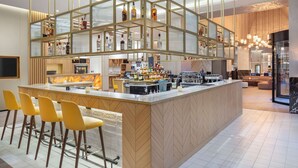Zona de bar moderna con una barra central, taburetes y una variedad de botellas de licores.