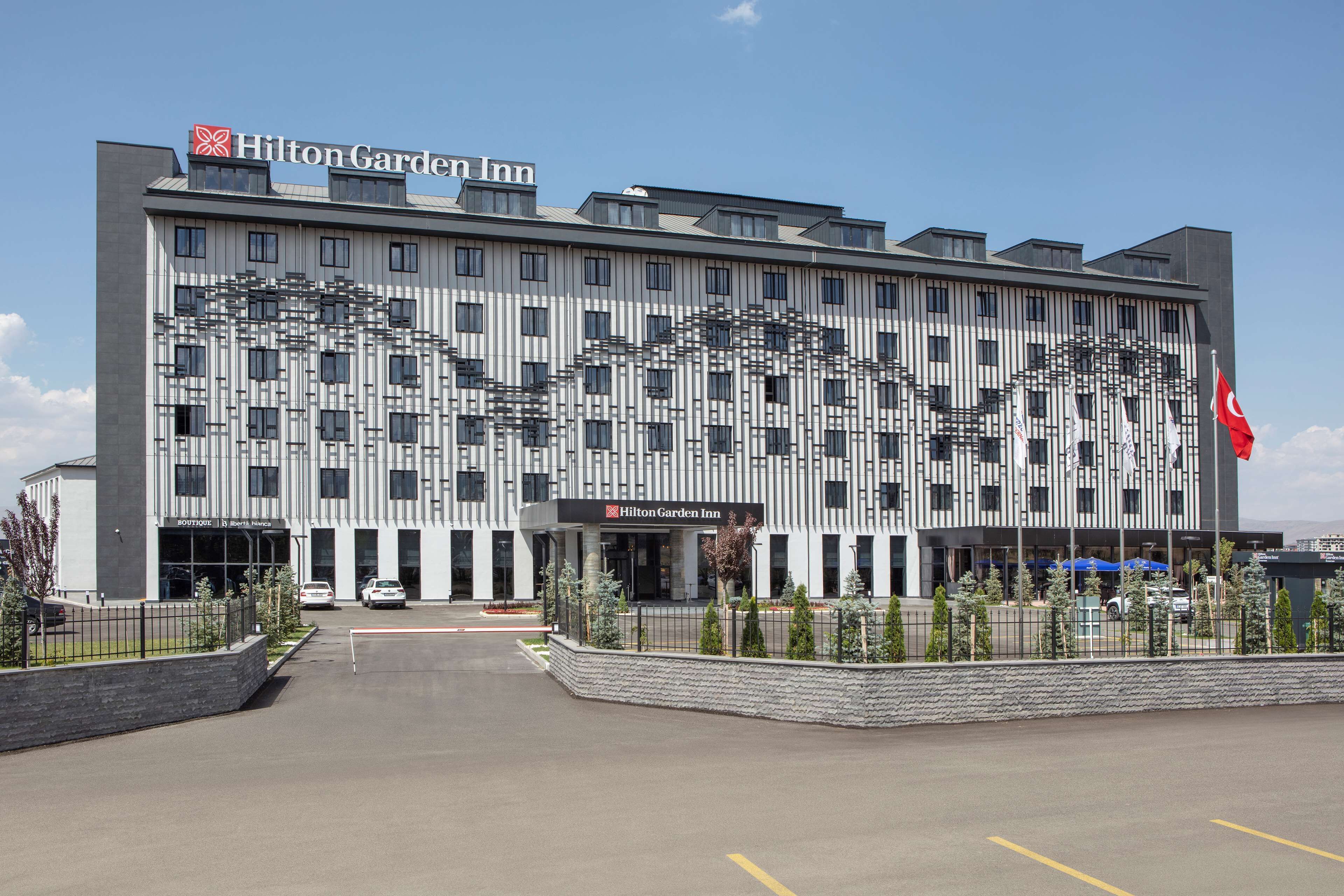 Ein Hilton Garden Inn Hotel mit moderner Architektur, mit gut sichtbarem Logo und einer Flagge.