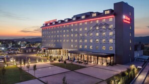 Un hotel moderno con una fachada destacada, ventanas amplias y un área exterior bien iluminada con asientos.