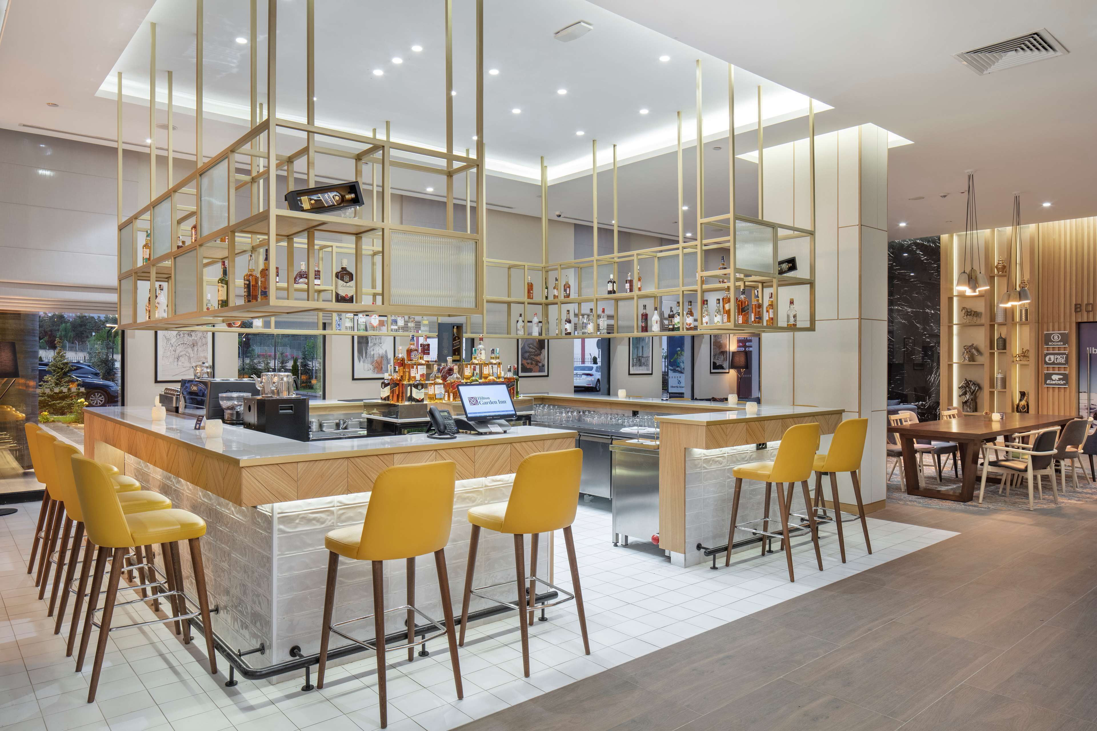 A modern bar area with a central island, bar stools, and a dining table with chairs.