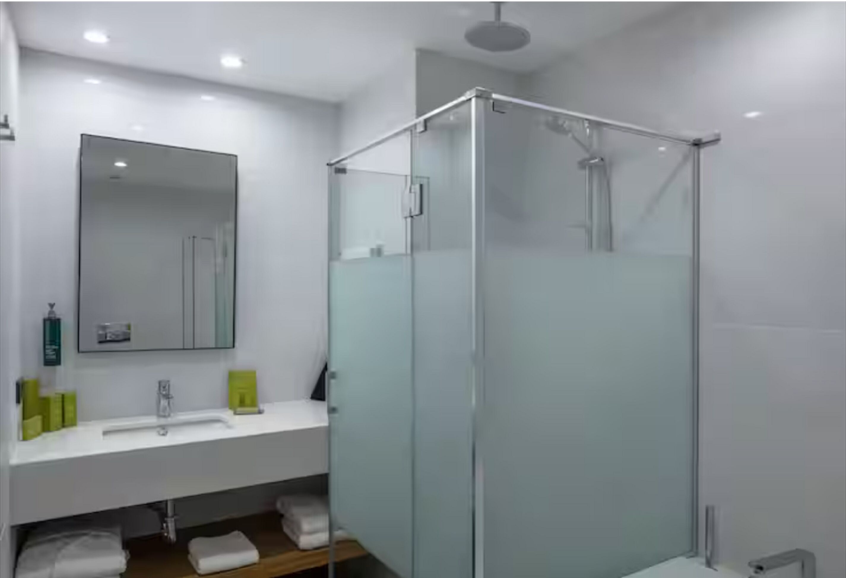 A modern bathroom with a glass-enclosed shower, a white sink, and a mirror above it.