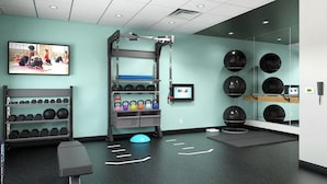 A gym with exercise equipment, a wall-mounted TV, and a mirror. - Tru by Hilton Chesterfield Township Detroit (New Baltimore)