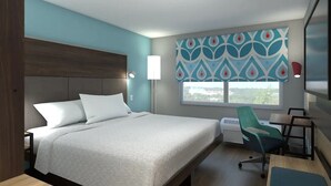 A hotel room with a large bed, a desk, a chair, a window with a view, and a flat-screen TV mounted on the wall. - Tru by Hilton Chesterfield Township Detroit (New Baltimore)