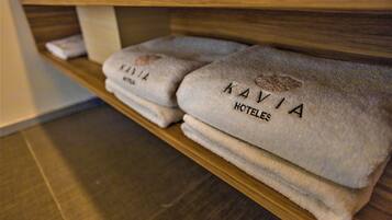 Ein Holzregal mit gefalteten Handtüchern, beschriftet mit 'KAVIA HOTELES'.