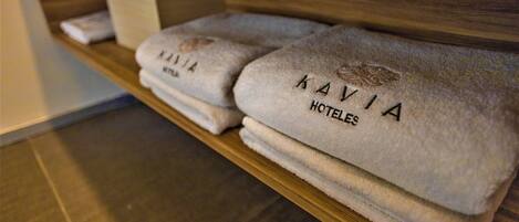 Un estante de madera con toallas dobladas, con la etiqueta "KAVIA HOTELES".