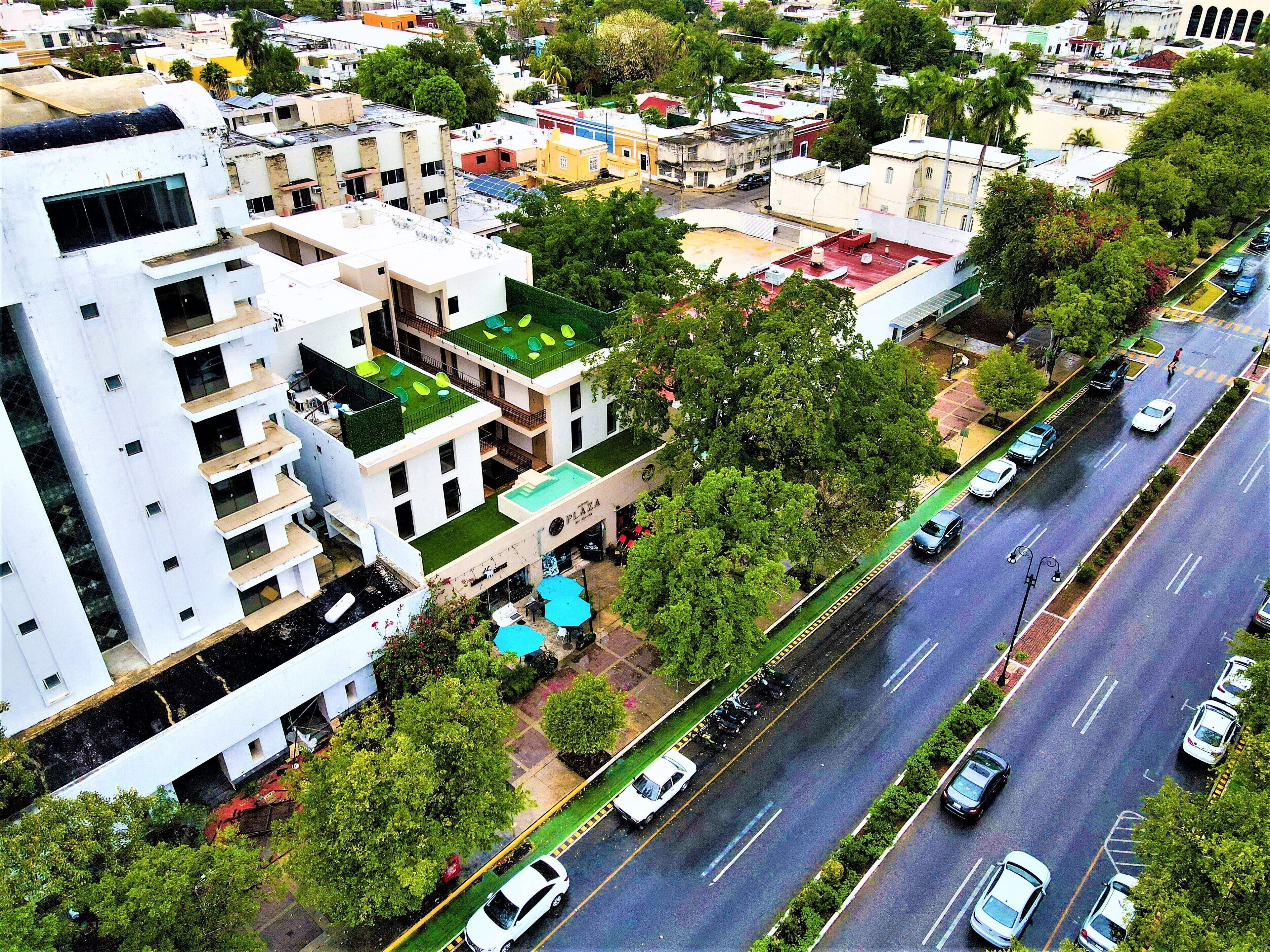 Un edificio de varios pisos con jardín en la azotea y un letrero visible que dice 'Plaza'.