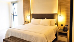 A modern bedroom with a large bed, bedside tables, and a bench. - Hotel Plaza by Kavia (Mérida)