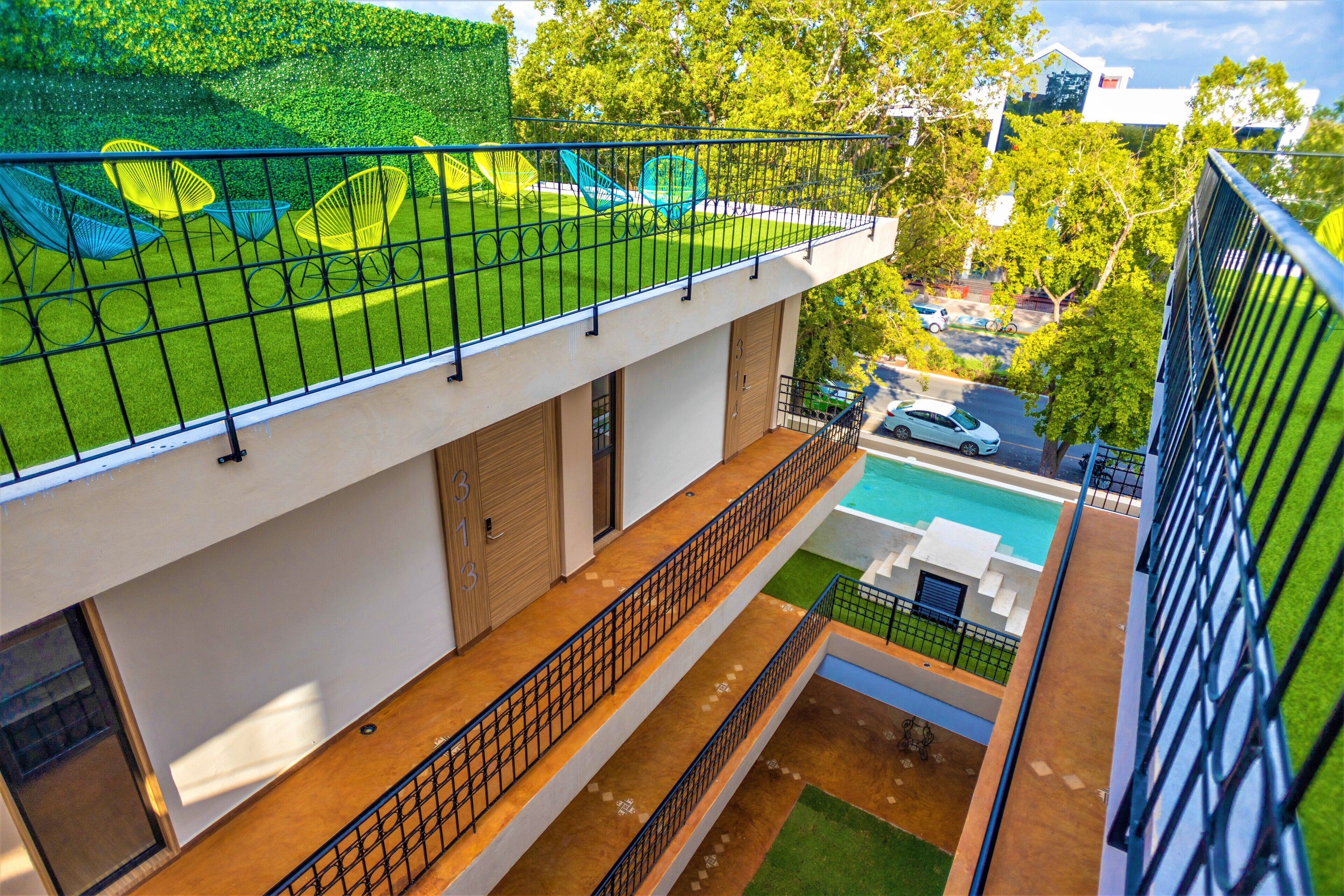 A modern building with a rooftop garden, a swimming pool, and a balcony with a railing.
