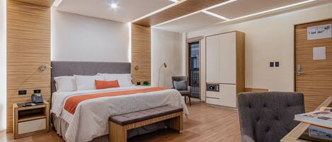 Una habitación de hotel moderna con una cama grande, un banco, un escritorio y una silla.