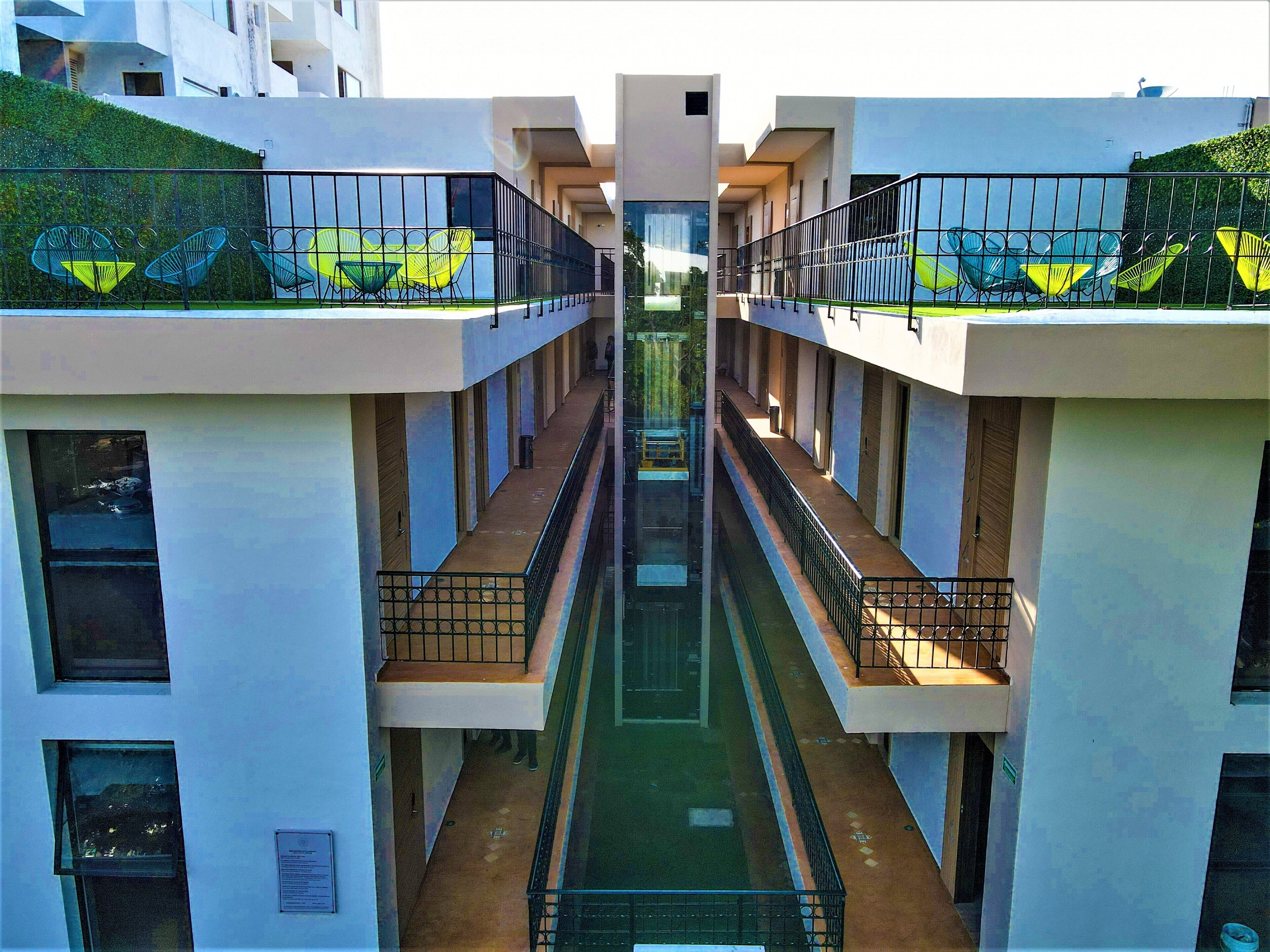 A modern building with a central atrium, balconies with railings, and a green roof.