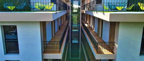 A modern building with a central atrium, balconies with railings, and a green roof.