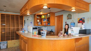 A reception area with wooden cabinets, a counter with various items, and a clock on the wall. - Tropic Island Resort (Port Aransas)