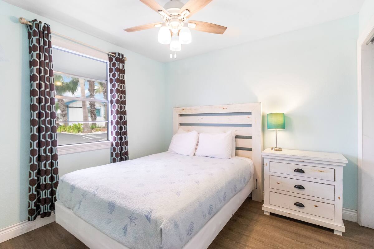 A bedroom with a bed, a nightstand, a lamp, and a ceiling fan.