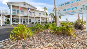 A resort building with a signboard listing amenities like hotel rooms, bungalows, and RV sites. - Tropic Island Resort (Port Aransas)